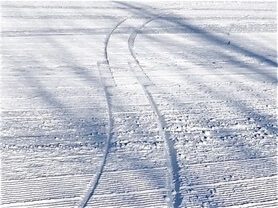 Ski tracks in the snow showing 2 pencil thin lines, then a flat section the length of one ski then 2 pencil thin lines again