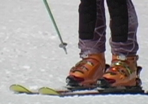 Skier from knees down showing skis flat on snow.