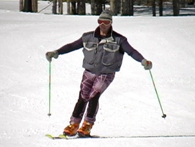 Skier standing tall rolling skis onto downhill edges