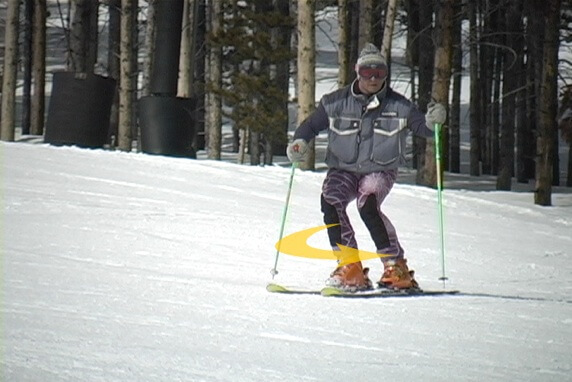 Photo of skier in transition. Curved arrow around lower legs.