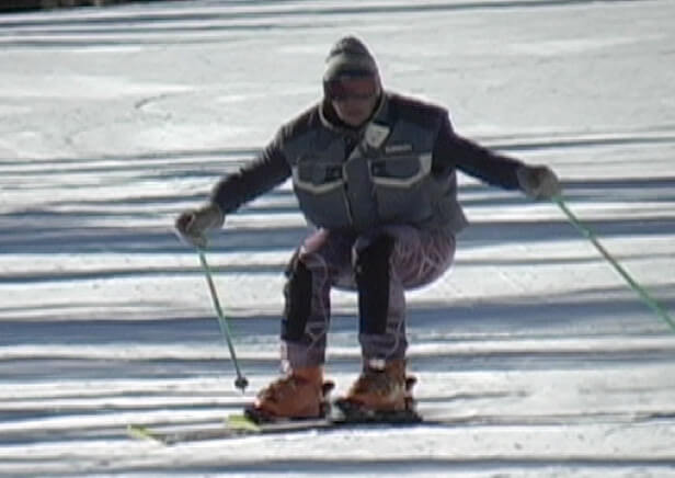 Photo of skier in transition, with deeply flexed legs, hips behind feet.